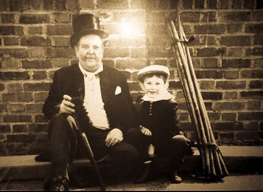 Archive photograph of two generations of Naish chimney sweeps, one in a top hat, with their brushes