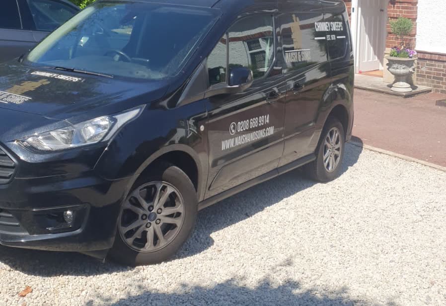 The black Naish & Sons van on a gravel drive outside a handsome period house