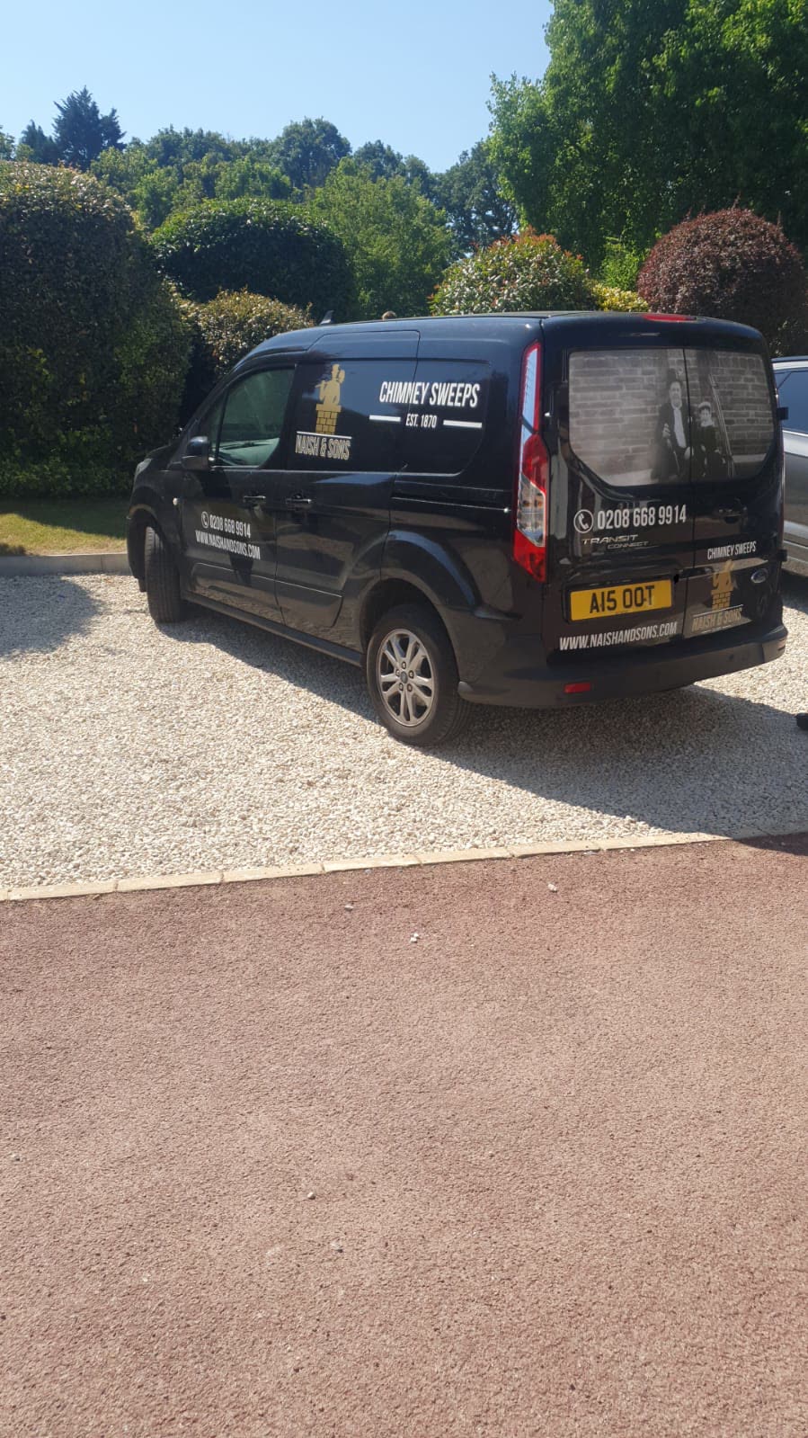 The rear of the black Naish & Sons chimney sweep van, with the historic family photograph displayed in the back window